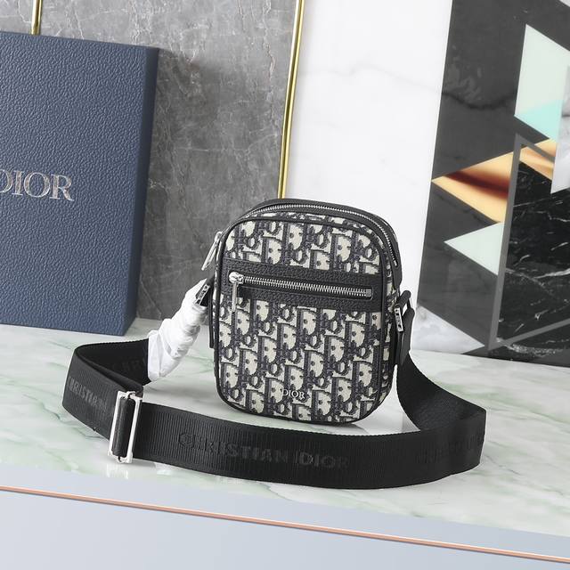 Dior 这款信使包是本季新品 精巧实用 是日常的理想良伴 采用米色和黑色 Oblique 印花面料精心制作 饰以黑色粒面牛皮革细节 拉链隔层和正面口袋可收纳各