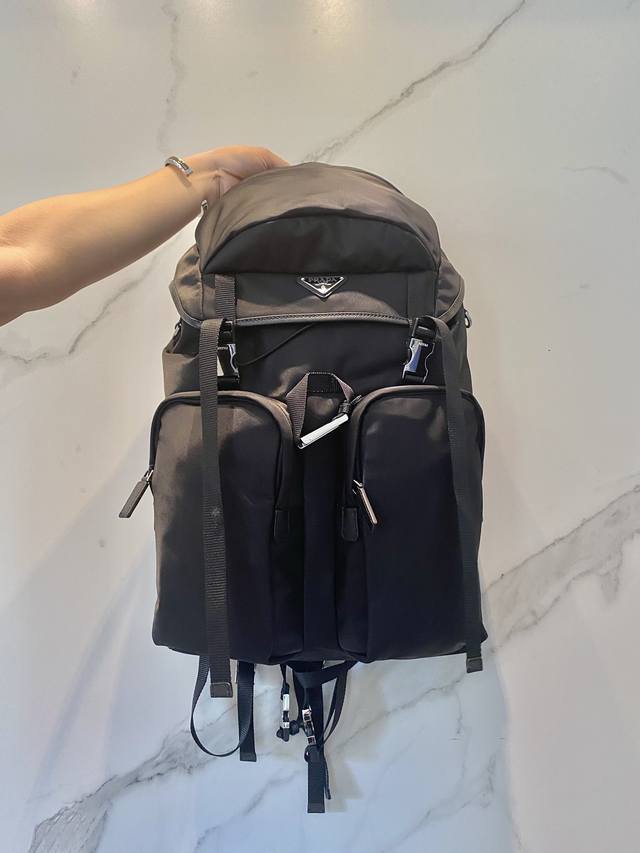 新款登山包2VZ019 这款双肩背包采用进口尼龙面料打造，颇具科技风范。背包的主隔层配翻盖和搭扣，后幅拉链式口袋，可调式编织尼龙饰带，两个外部拉链式口袋和两个束